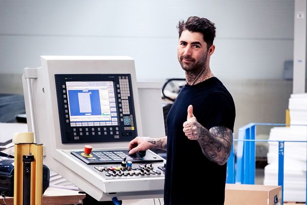 Mitarbeiter, der eine Maschine bedient gibt Daumen hoch