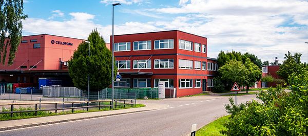 rotes Firmengeb&auml;ude mit Produktionshalle umgeben von gr&uuml;ner Natur