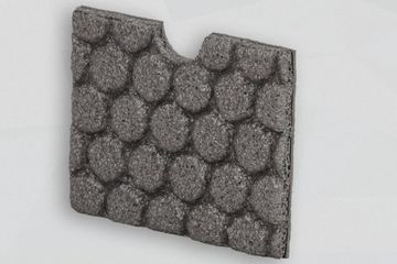 Graue Schaumstoffplatte mit Noppenmuster stehend vor grauem Hintergrund